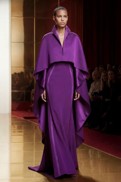 这组造型展示的是亚历克西·马毕 Alexis Mabille 2026 春夏高级定制系列。秀场以高饱和宝石色展开叙事，紫晶、祖母绿、香槟金与糖果粉形成强烈视觉层级，大体积斗篷、夸张蝴蝶结与流线礼服共同建立法式戏剧感。设计师延续品牌标志性的“现代礼服主义”，在高定轮廓中加入轻结构处理，使华丽不再厚重，而是带有舞台般的流动性与女性力量。整体呈现出一种介于歌剧盛典与数字时装之间的未来浪漫。——来自顽石频道国际流行趋势分析。